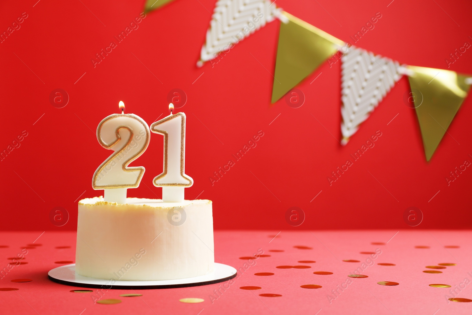 Photo of Coming of age party - 21st birthday. Delicious cake with number shaped candles on red background, space for text