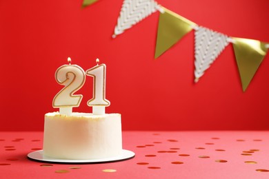 Coming of age party - 21st birthday. Delicious cake with number shaped candles on red background, space for text