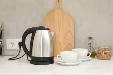 Photo of Electric kettle and cups on counter in kitchen