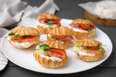 Photo of Delicious profiteroles with tasty filling on grey wooden table, closeup