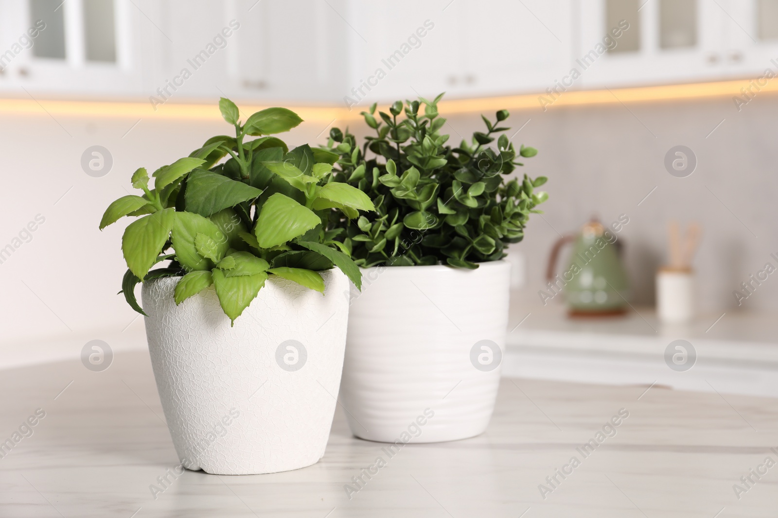 Photo of Artificial potted herbs on white marble table in kitchen, space for text. Home decor