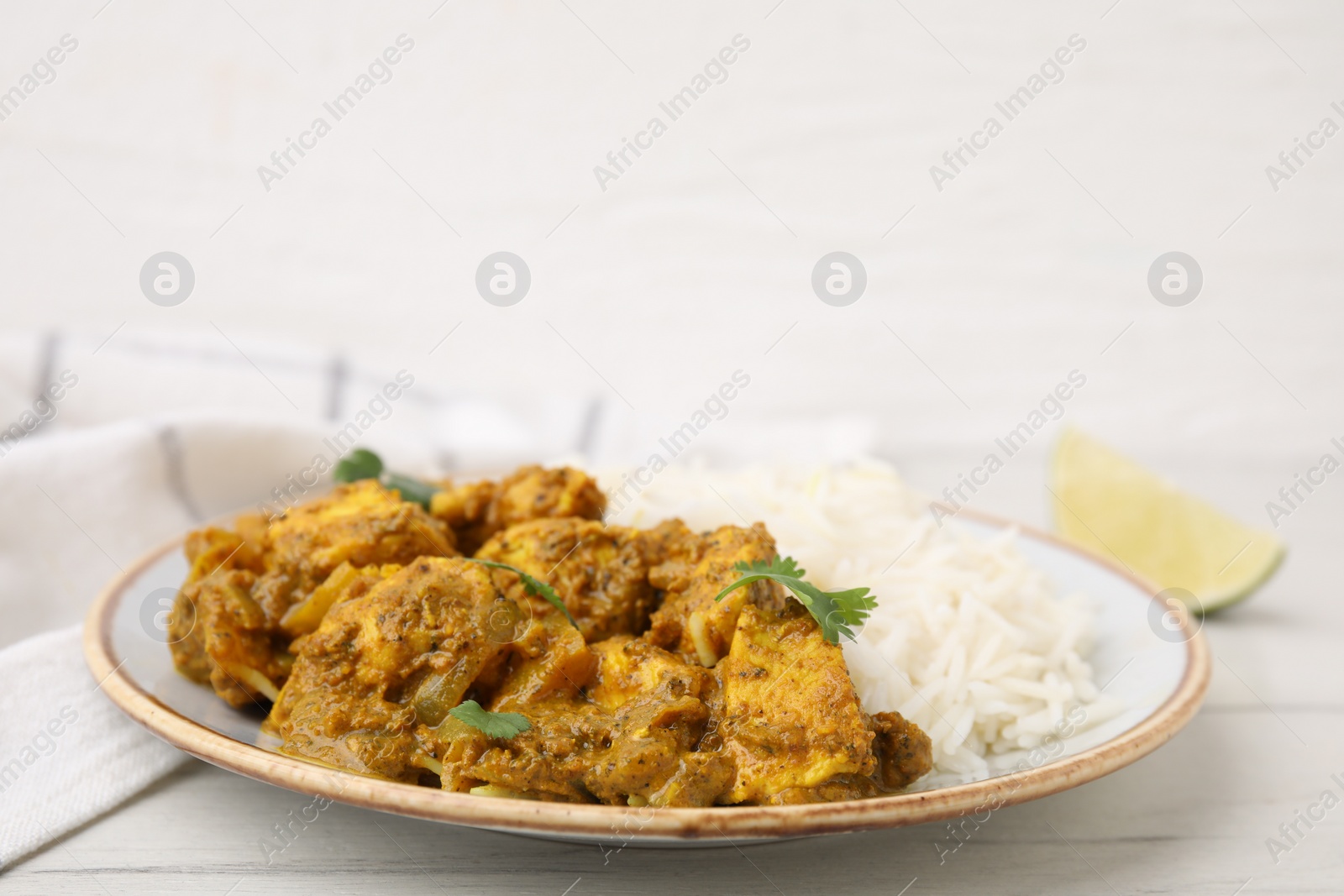 Photo of Delicious chicken curry with rice on white wooden table