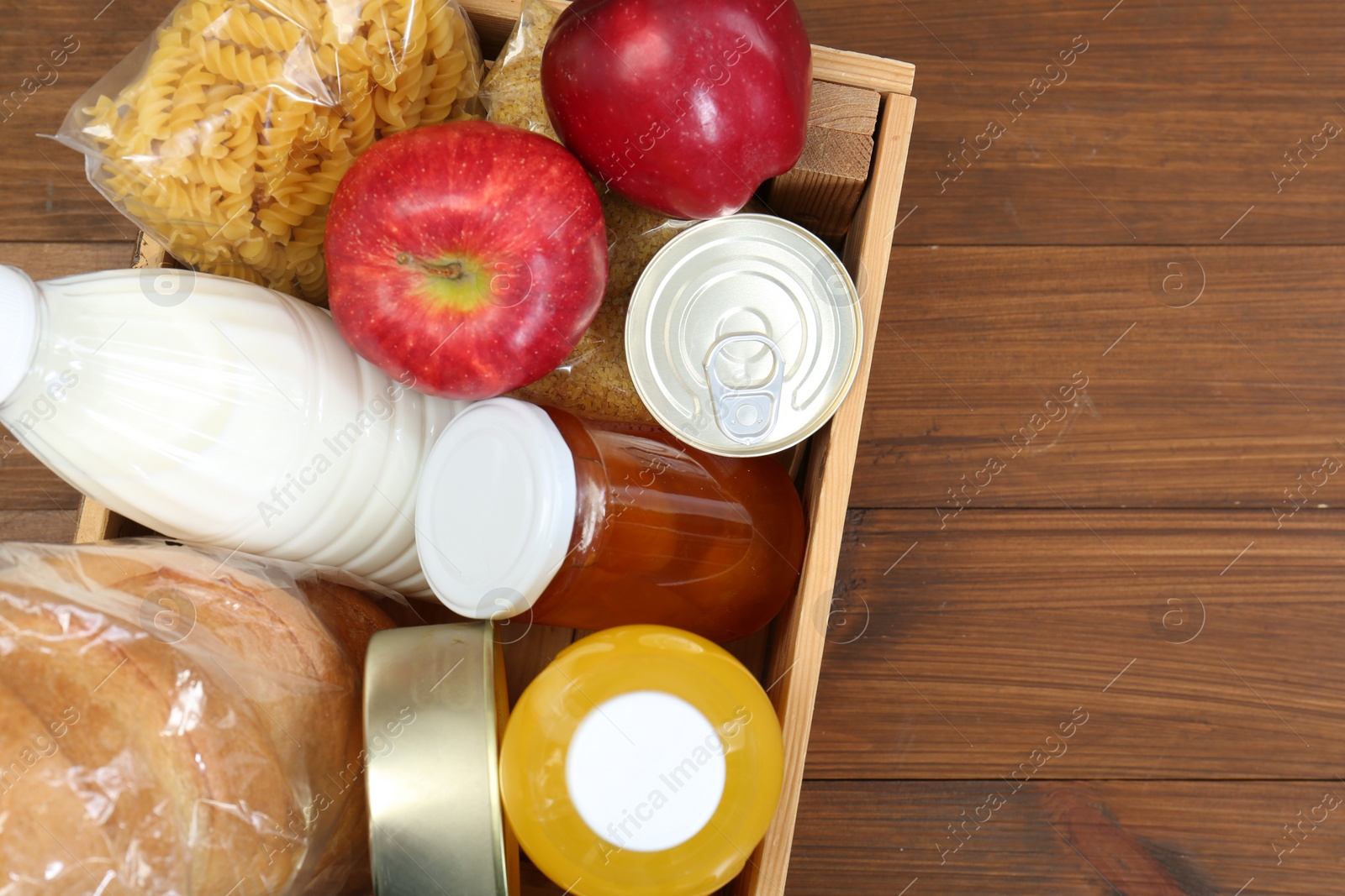 Photo of Humanitarian aid. Different food products for donation in crate on wooden table, top view