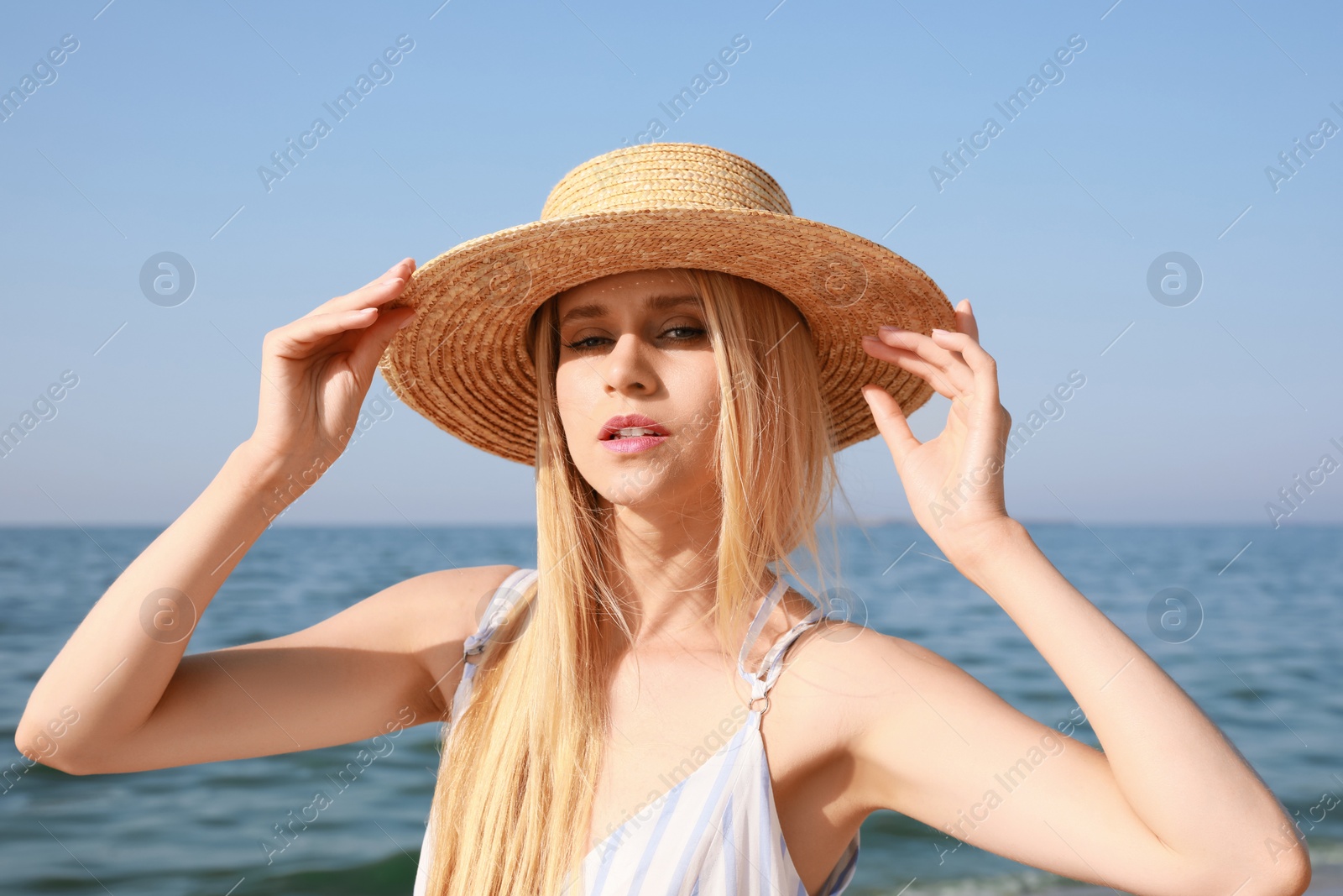 Photo of Beautiful young woman with straw hat near sea on sunny day in summer