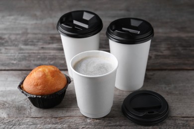 Coffee to go. Paper cups with tasty drink and muffin on wooden table