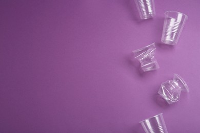 Photo of Plastic cups on purple background, flat lay. Space for text