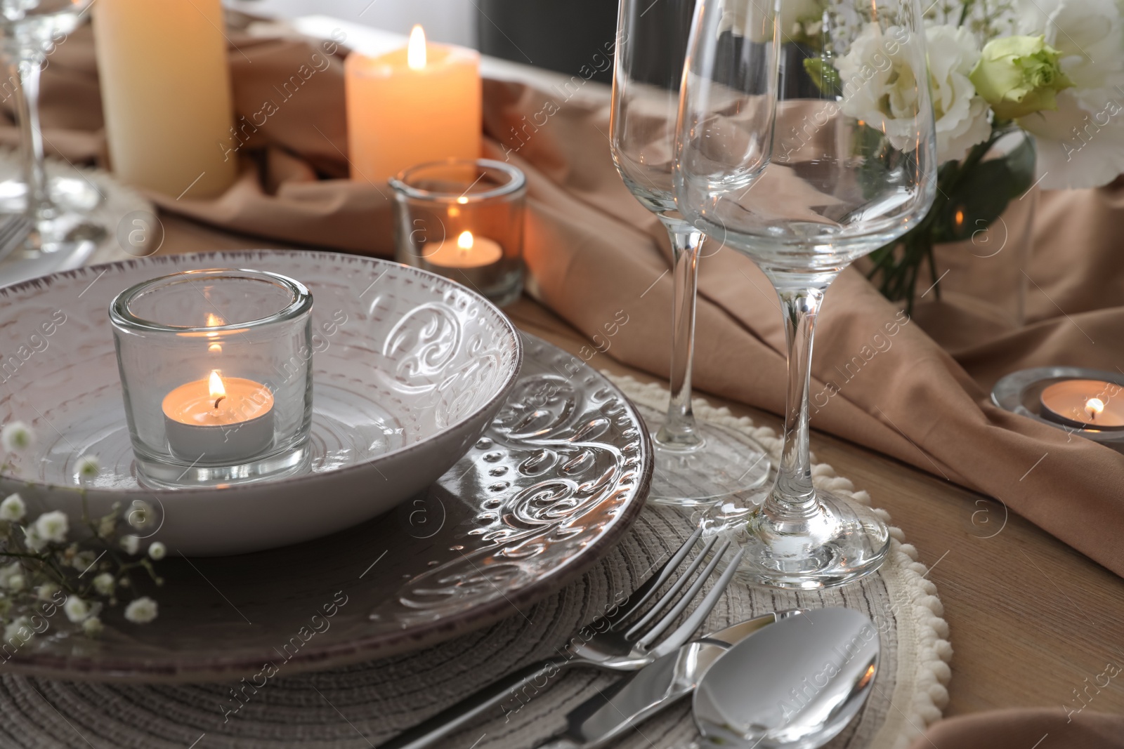 Photo of Festive table setting with beautiful candle and floral decor, closeup