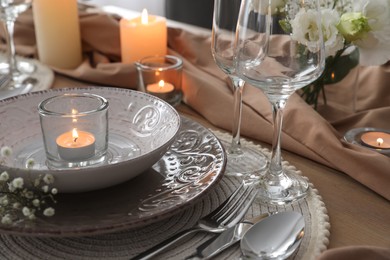 Festive table setting with beautiful candle and floral decor, closeup