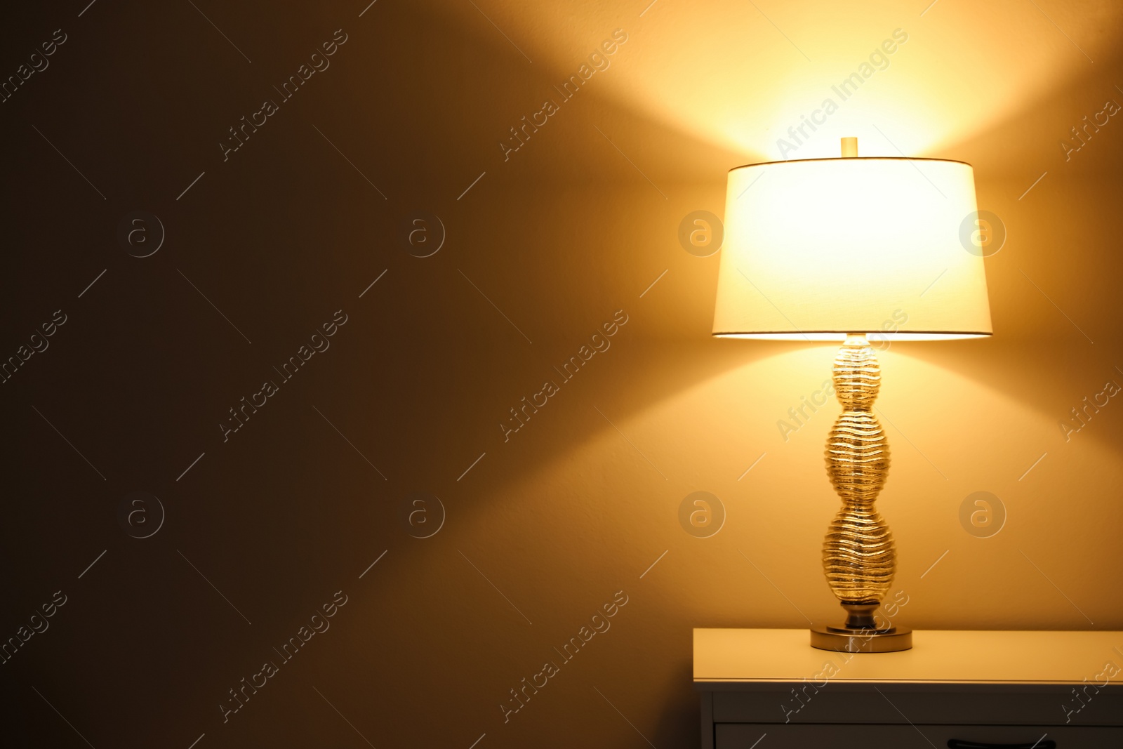 Photo of Stylish glowing  night lamp on table in room. Space for text