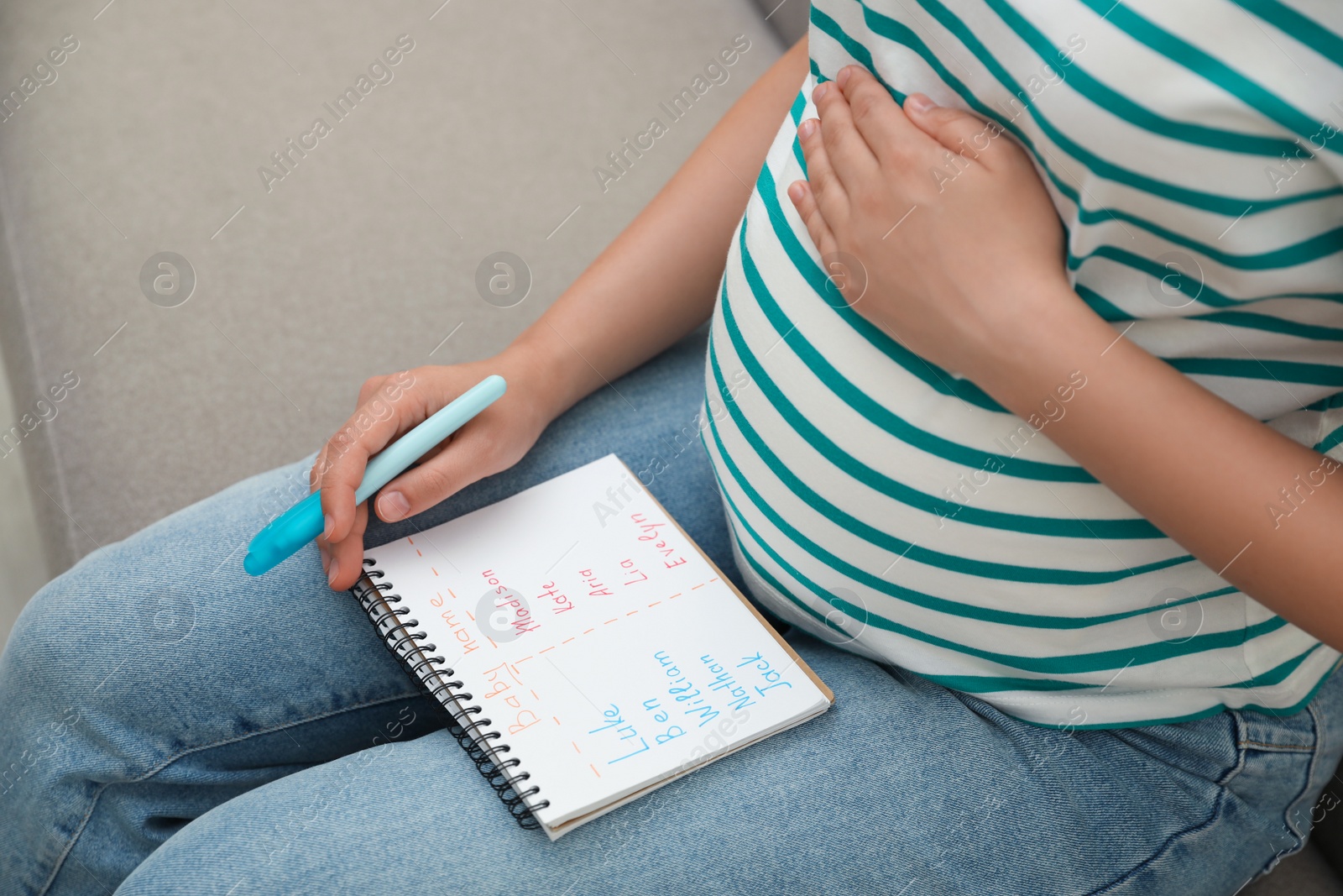 Photo of Pregnant woman with baby names list sitting on sofa, closeup