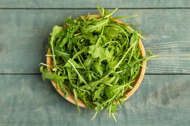 Photo of Fresh arugula on blue wooden table, top view