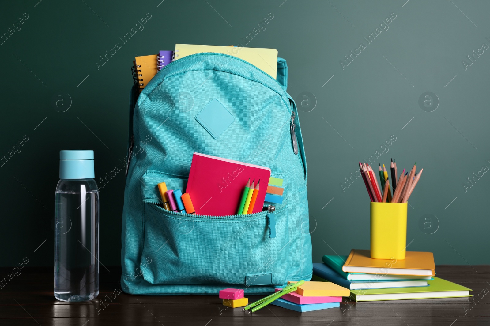 Photo of Backpack with different school stationery on white table near chalkboard