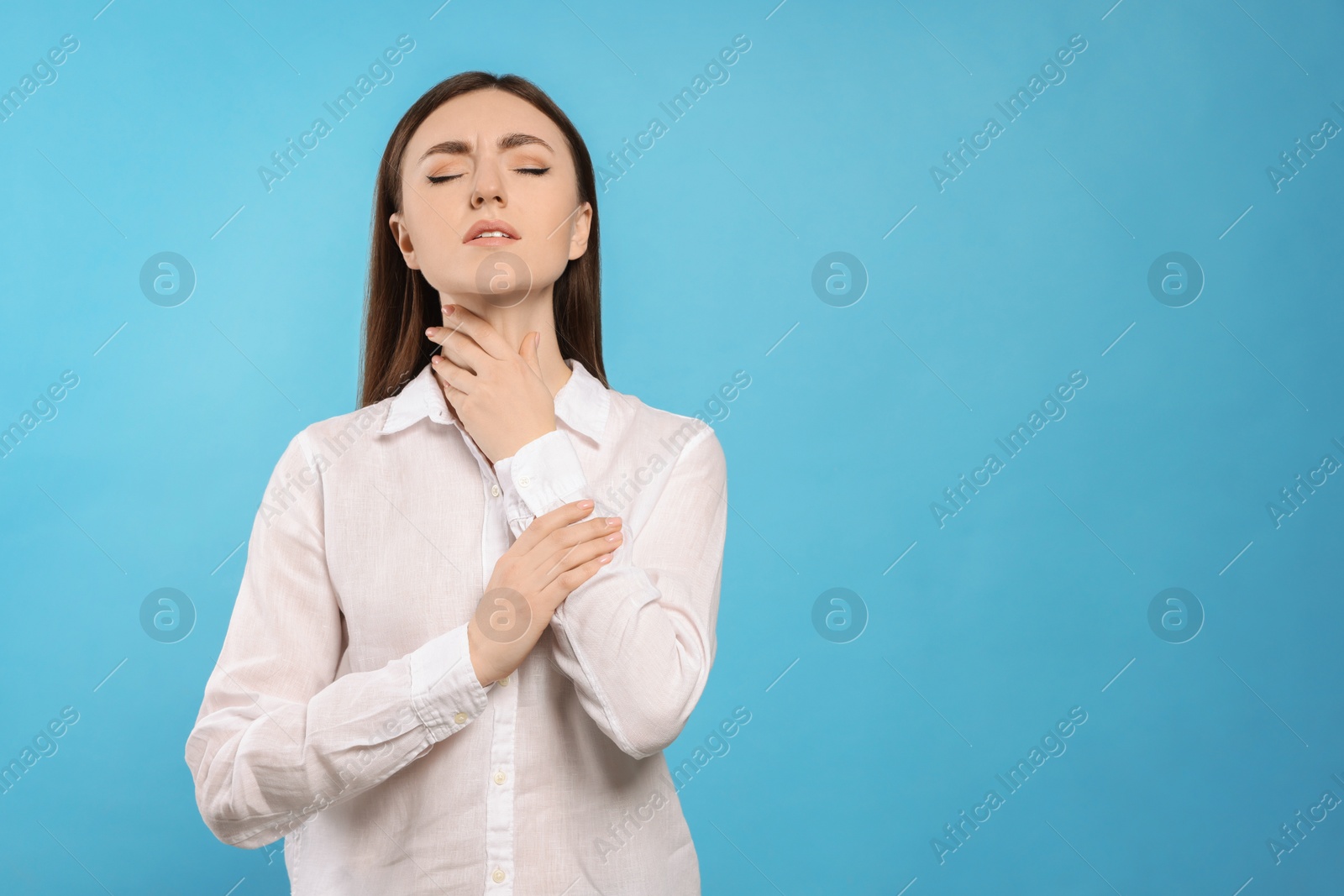 Photo of Young woman with sore throat on light blue background. Space for text