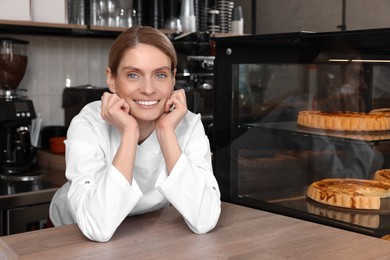 Photo of Professional baker at cashier desk near showcase in store