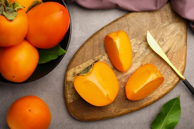 Delicious ripe persimmons and knife on light gray table, flat lay