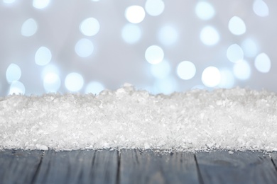 Photo of Heap of snow on wooden surface against blurred background. Christmas season