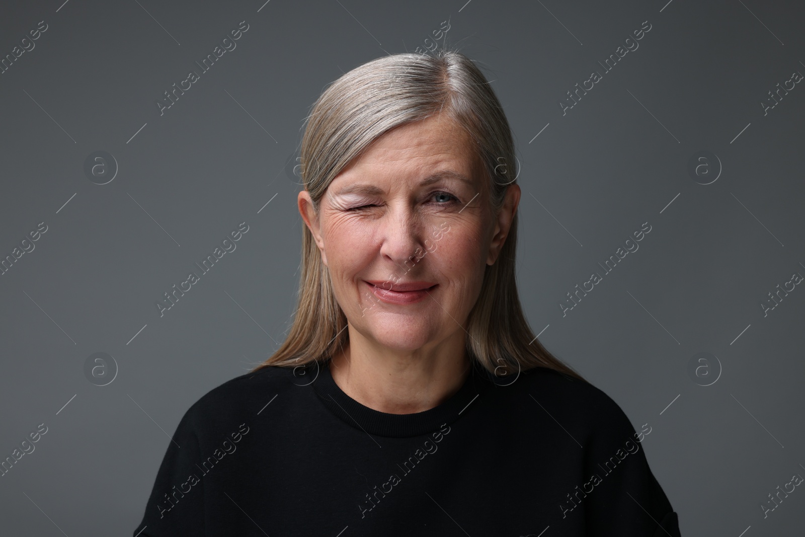 Photo of Personality concept. Portrait of woman winking on gray background