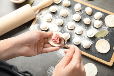 Photo of Woman cooking delicious dumplings over table, above view