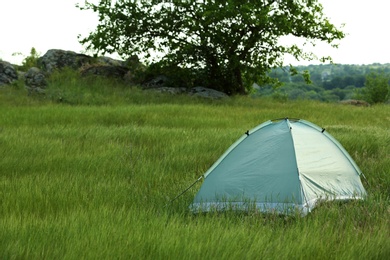 Photo of Modern camping tent in green field. Space for text