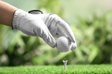 Photo of Player putting golf ball on tee against blurred background, closeup