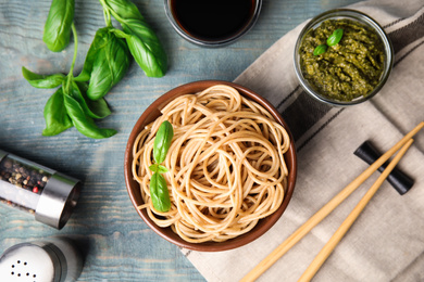 Tasty buckwheat noodles served on blue wooden table, flat lay