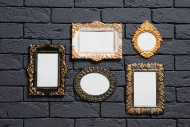 Photo of Empty vintage frames hanging on dark brick wall. Mockup for design