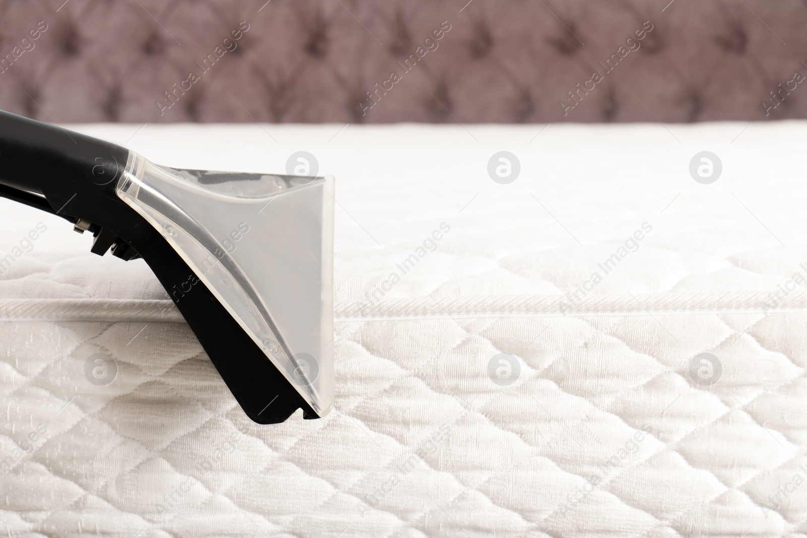 Photo of Using modern vacuum cleaner for mattress disinfection, closeup. Space for text