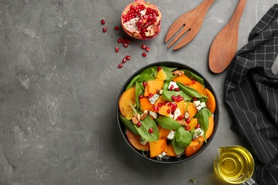 Delicious persimmon salad served on grey table, flat lay. Space for text