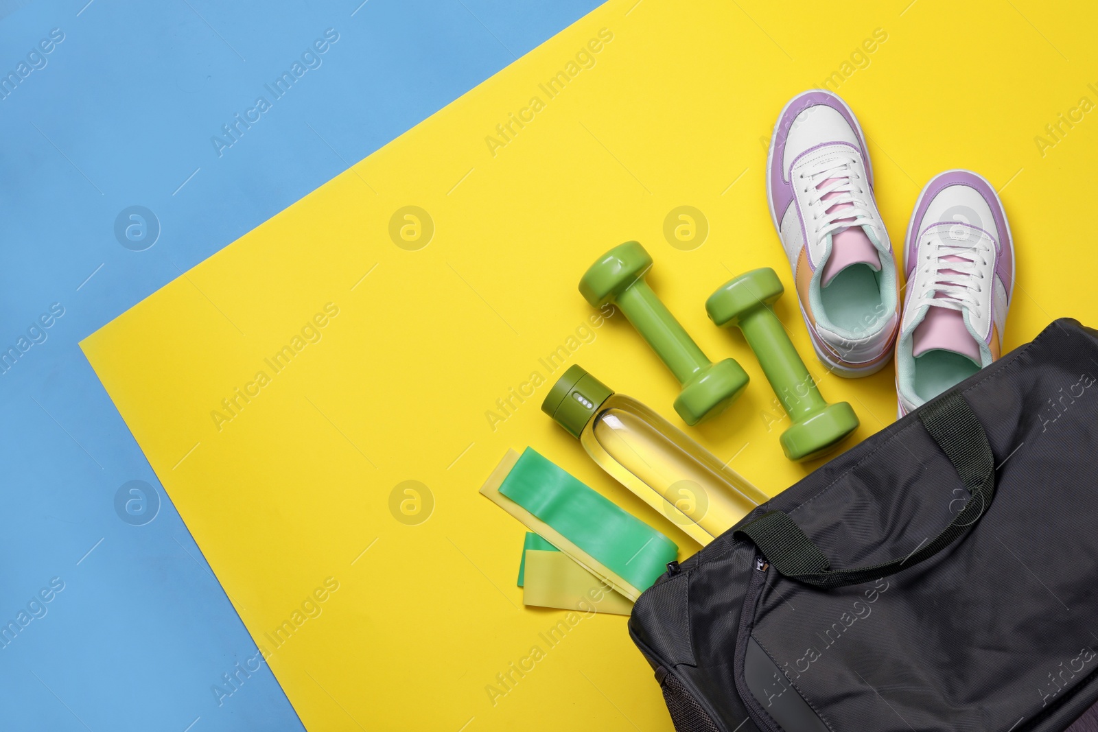 Photo of Gym bag and sports equipment on color background, flat lay. Space for text