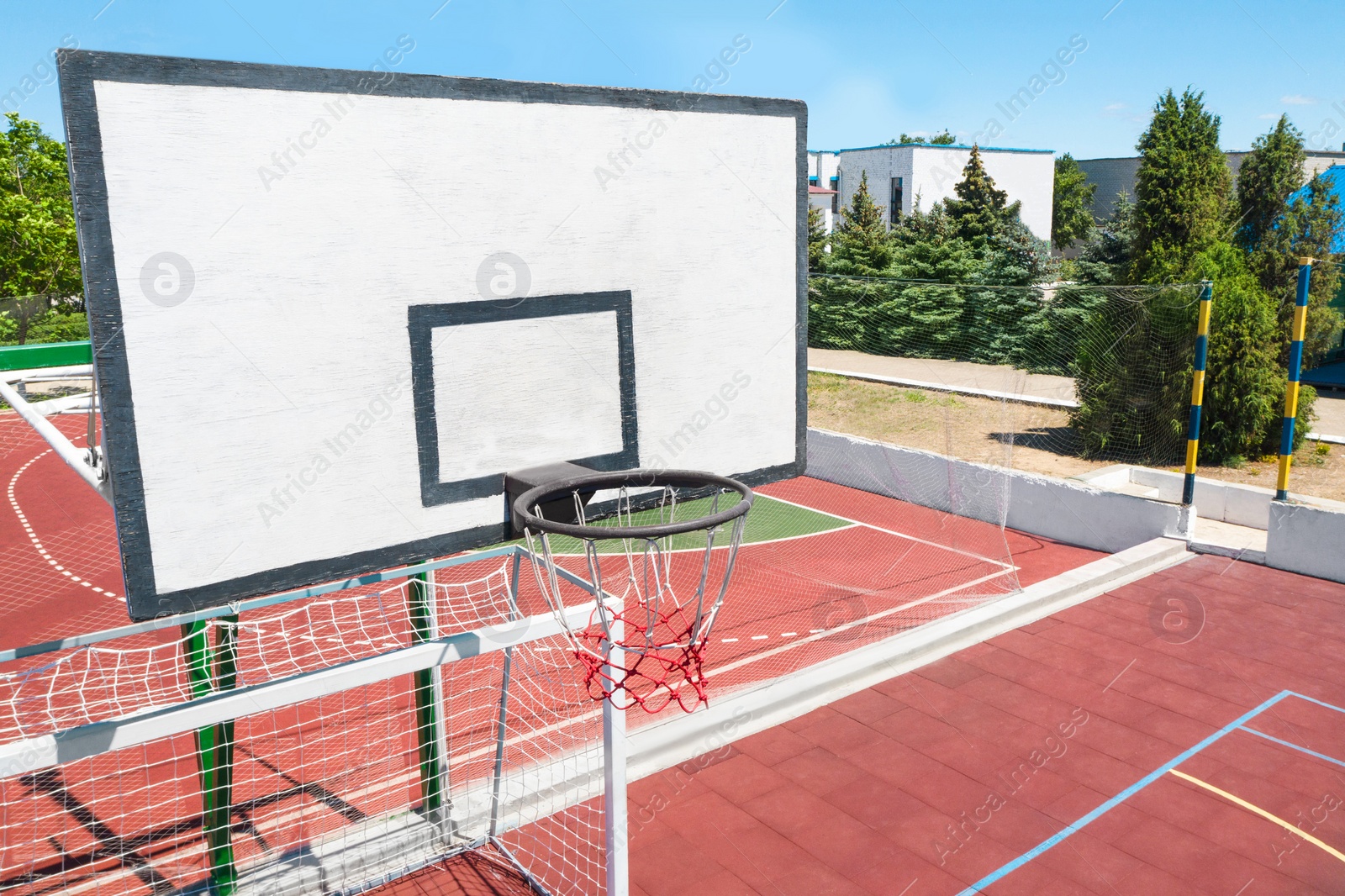 Image of Basketball backboard over football gat at outdoor sports complex on sunny day