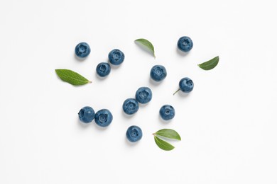 Tasty fresh blueberries with green leaves on white background, flat lay