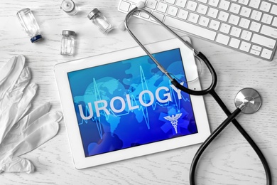 Photo of Tablet with word "UROLOGY" and medical items on table, top view