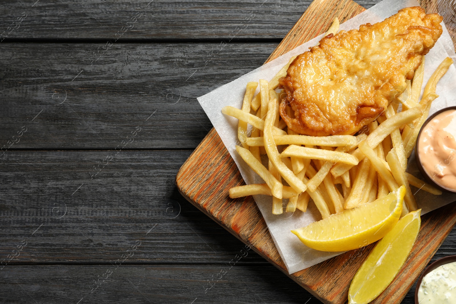 Photo of Board with British traditional fish and potato chips on wooden background, top view. Space for text