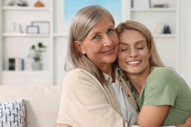 Photo of Happy mature mother and her daughter hugging at home