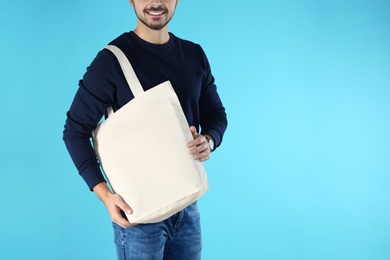 Young man holding textile bag on color background, closeup. Mockup for design