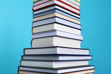 Photo of Stack of hardcover books on light blue background, closeup