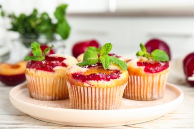 Delicious cupcakes with plums on white wooden table, closeup