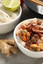 Seafood and other products for cooking wok on grey table, closeup