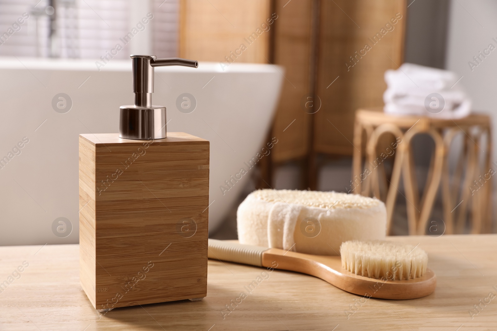 Photo of Dispenser of liquid soap, brush and loofah on wooden table in bathroom, space for text