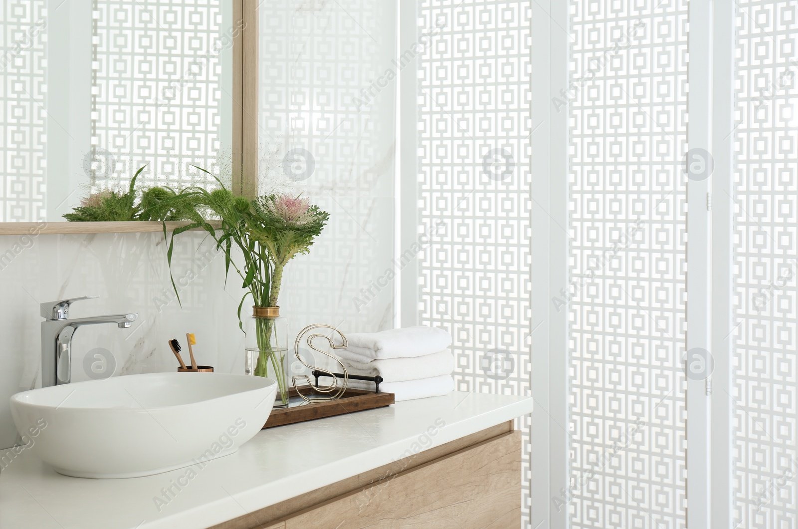 Photo of Bathroom counter with stylish vessel sink and bouquet. Interior design