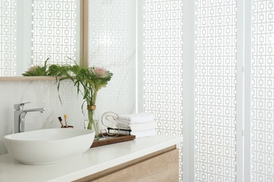 Bathroom counter with stylish vessel sink and bouquet. Interior design