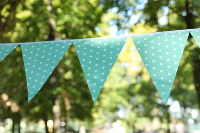 Photo of Light blue bunting flags in park. Party decor