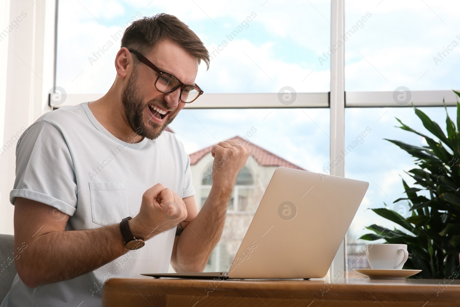 Photo of Emotional man participating in online auction using laptop at home