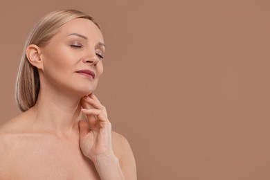 Photo of Beautiful woman touching her neck on beige background, space for text