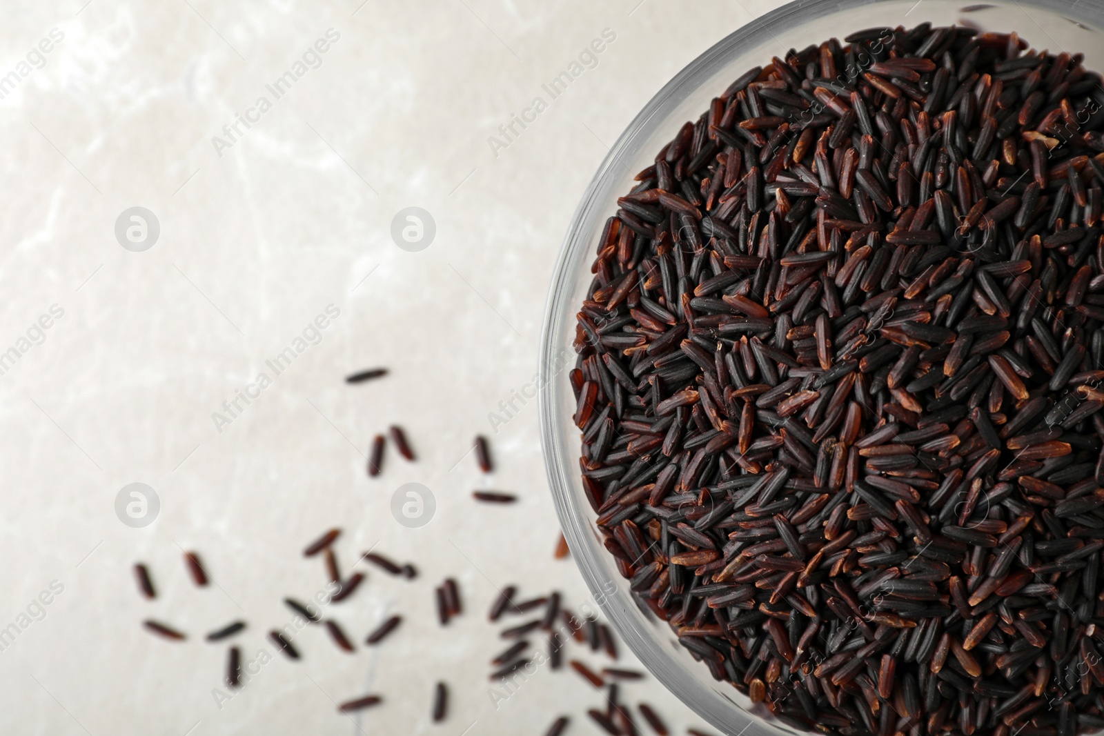 Photo of Bowl with brown rice on table, top view. Space for text