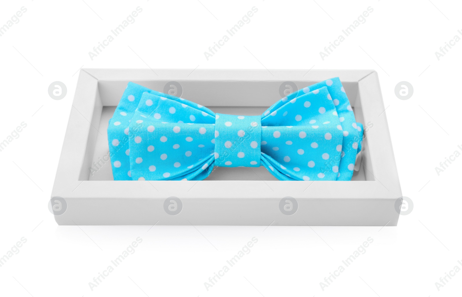 Photo of Stylish light blue bow tie with polka dot pattern in box on white background