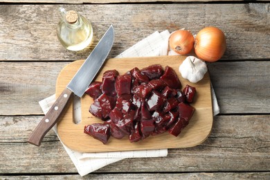 Photo of Cut raw beef liver and products on wooden table, flat lay