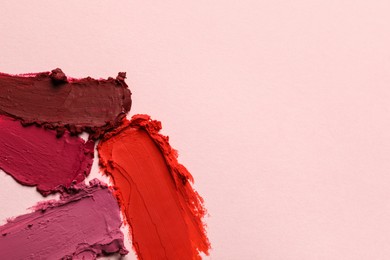 Photo of Smears of different bright lipsticks on light background, top view. Space for text