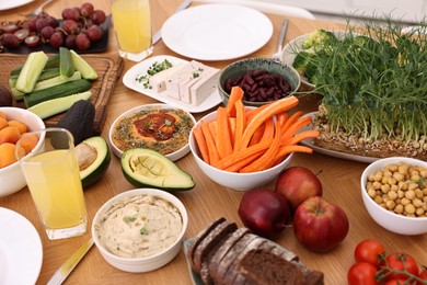 Healthy vegetarian food and glasses of juice on wooden table