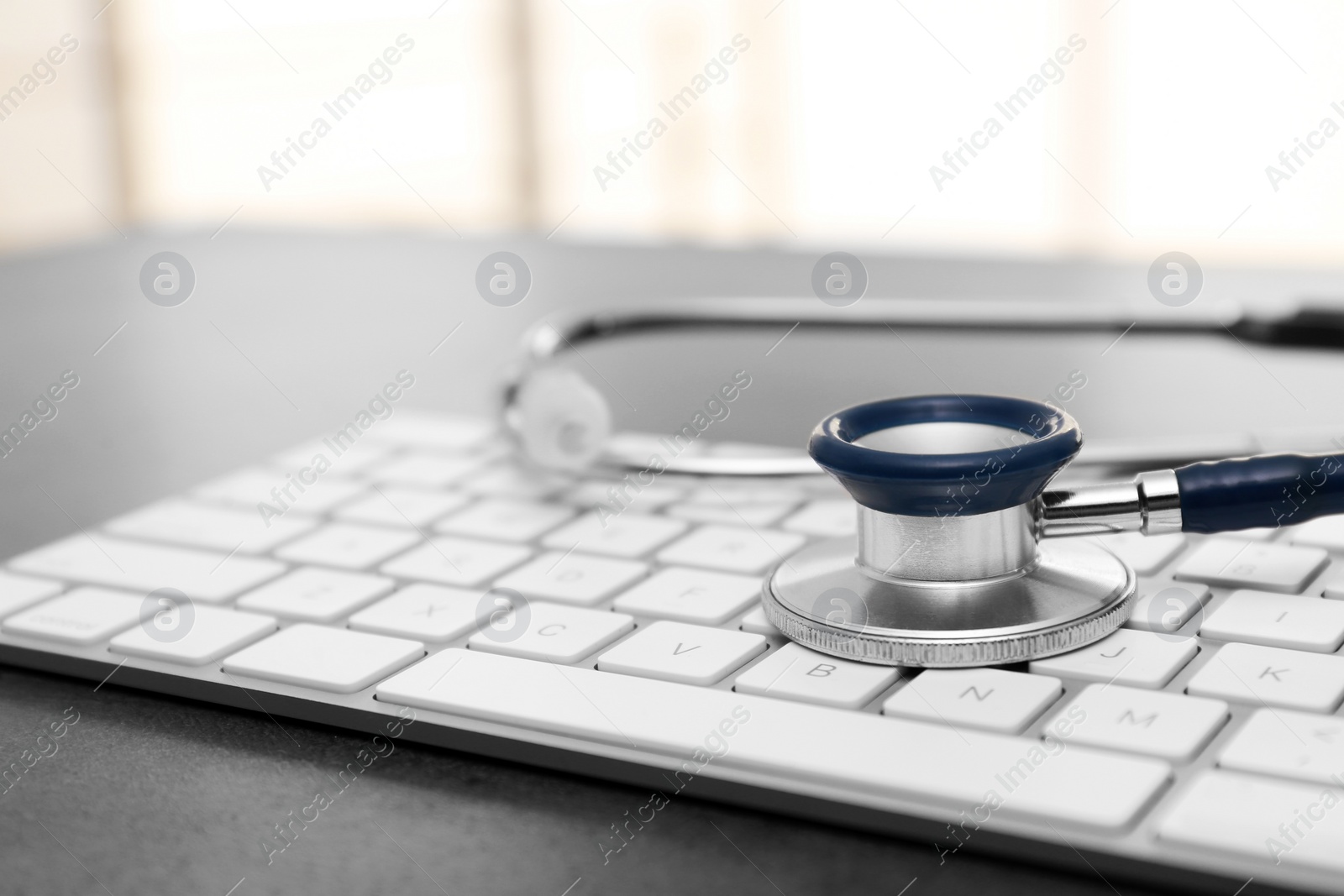 Photo of Modern keyboard and stethoscope on table. Technical support concept